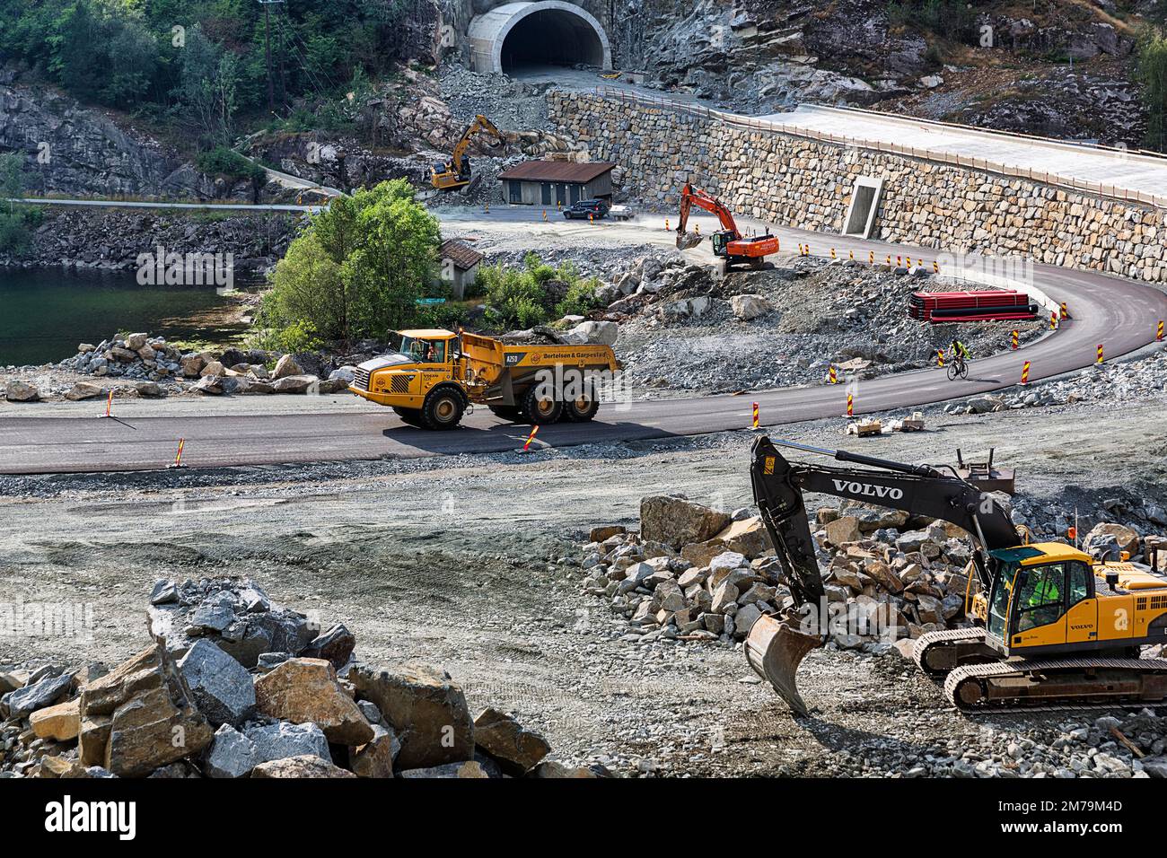 Vehicles and construction workers on road construction site in front of road tunnel, construction of new road in rocky area, Vestland, Norway Stock Photo