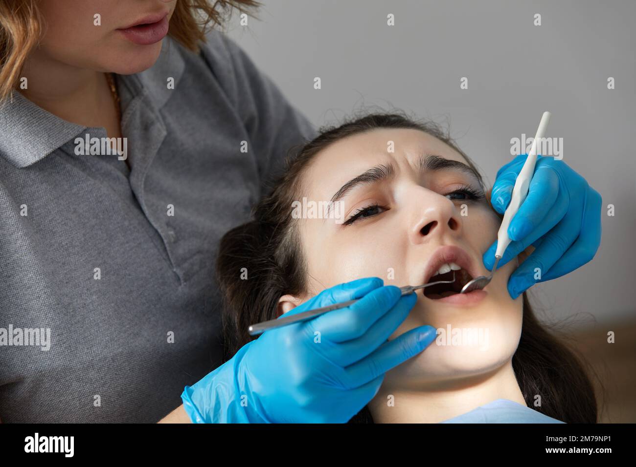 Dentist checking teeth of a female patient with dental mirror Stock