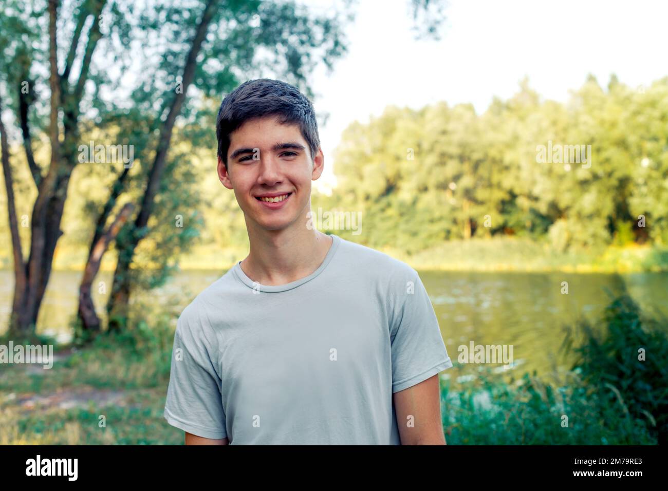 A young man with black hair smiling. Portrait of a gay in nature Stock Photo