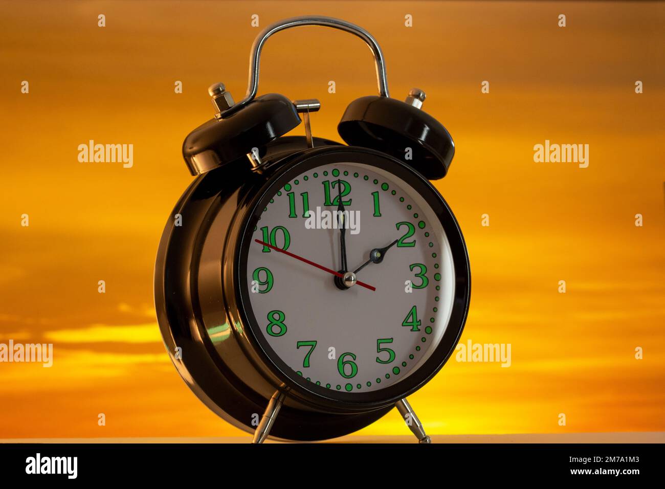 Symbol image of the time changeover to summer time time: Close-up of an alarm clock against a beautiful evening sky Stock Photo