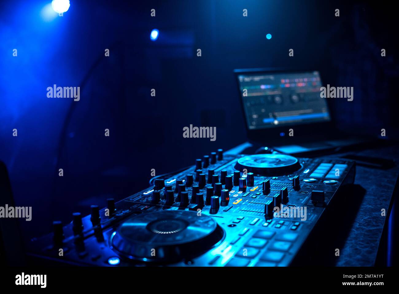 professional DJ music controller in booth in night club under blue ...