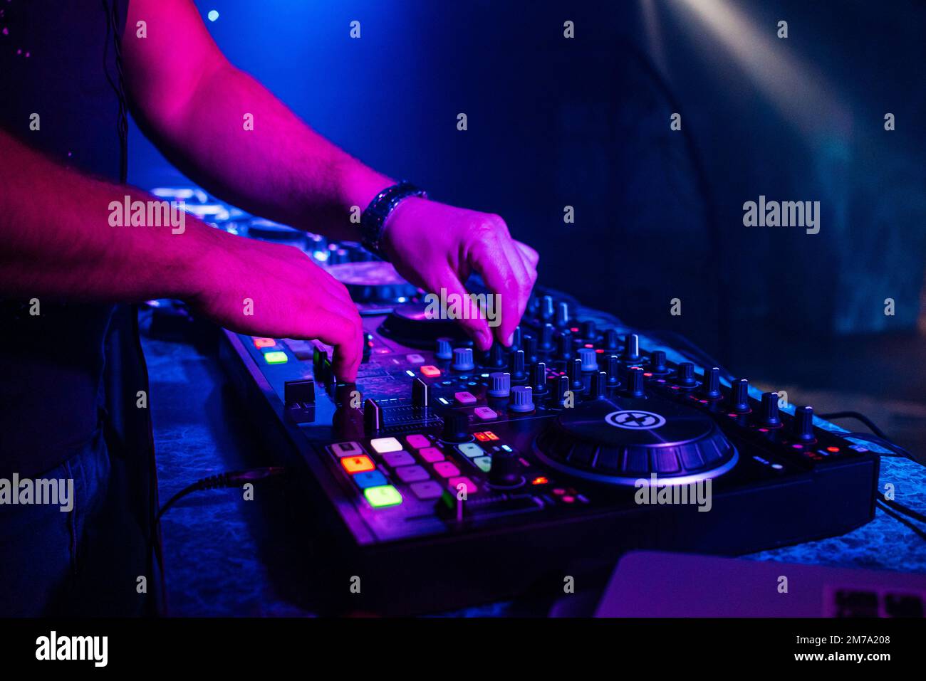 hands of a DJ playing music on a mixer at a concert in a
