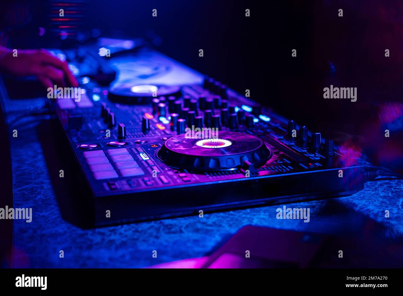 DJ mixer controller at a party in a by multicolored light