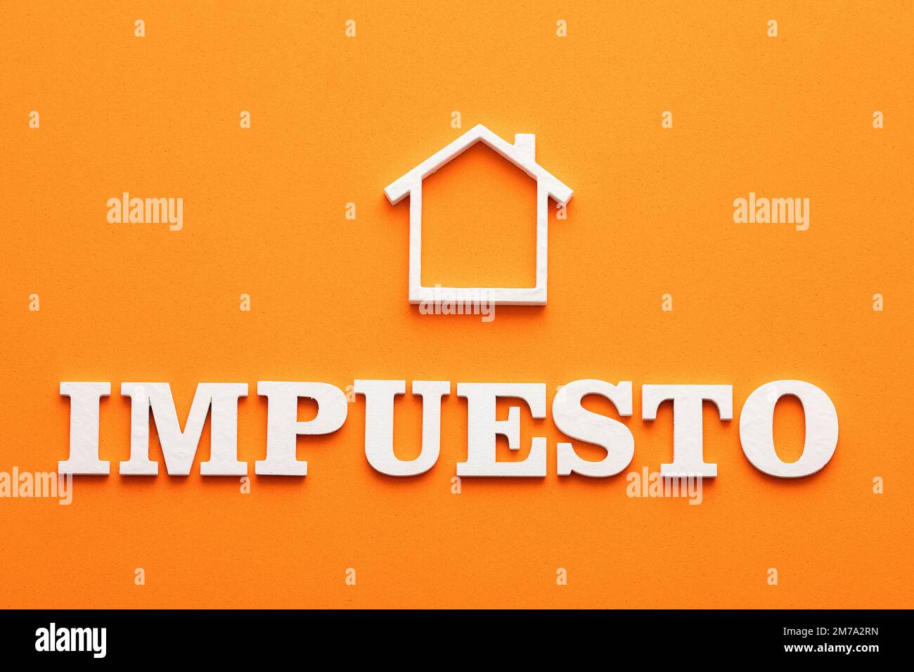 Real estate tax in spanish letters White house on orange foamy Stock