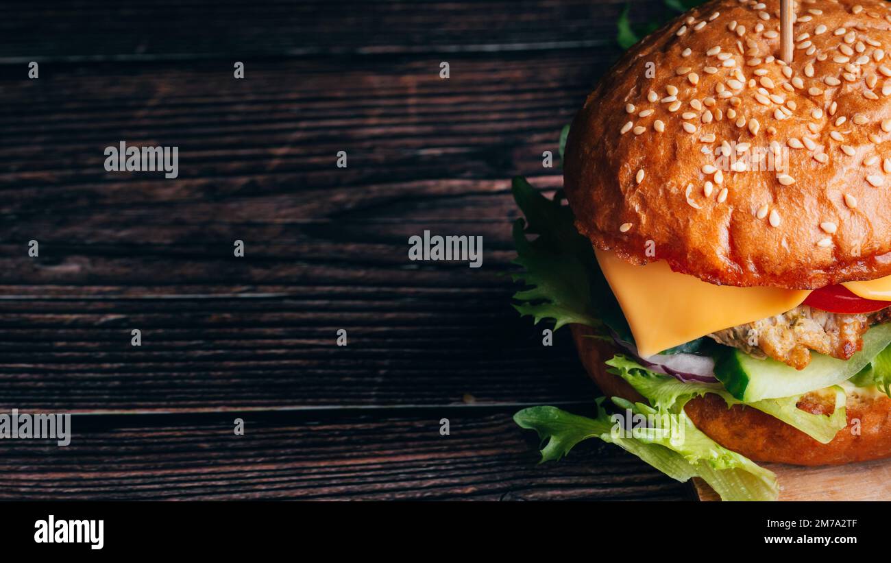 juicy delicious Burger with meat, cheese, lettuce, tomato and onion close-up on wooden background with copy space Stock Photo