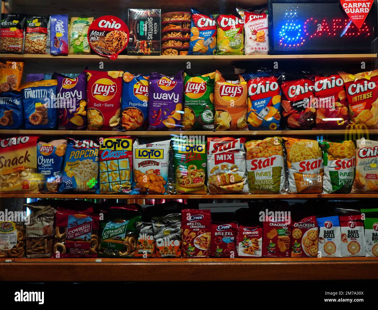 Bags of snacks of different brands on shelves in the window of food