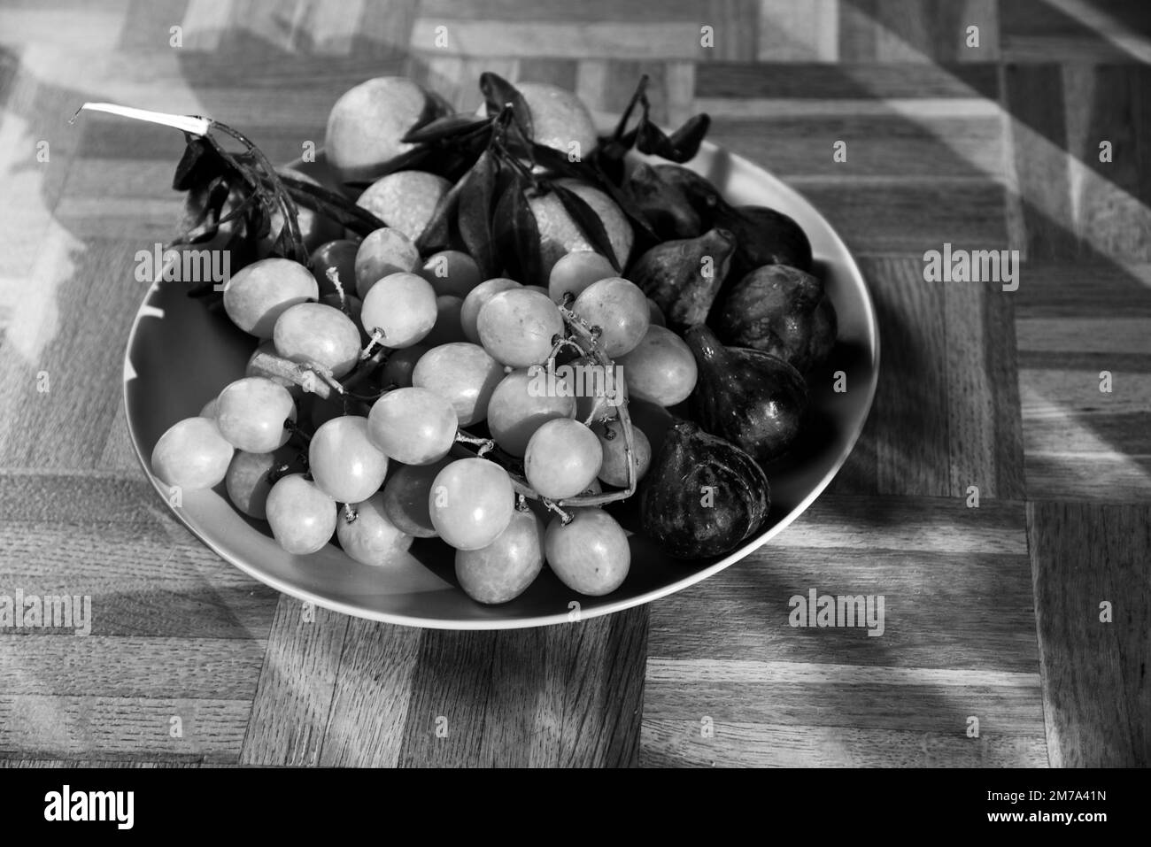 Different organic fruits from the local farmer market on plate on old rustic wooden surface.  Seasonal fruit background. Black white photography Stock Photo