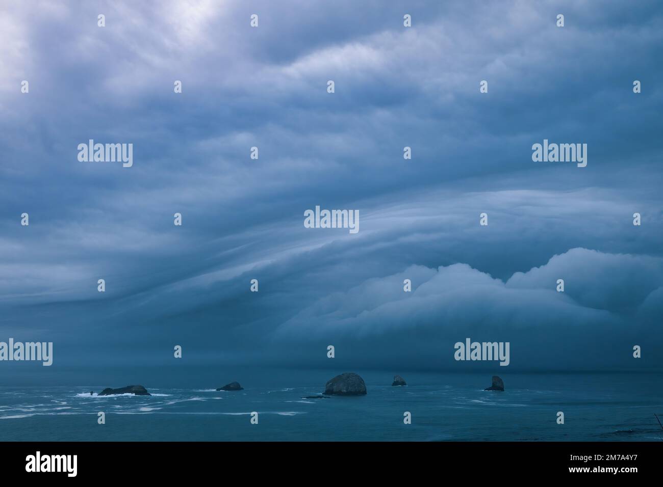 Storm clouds from bomb cyclone over sea stacks in the ocean Stock Photo