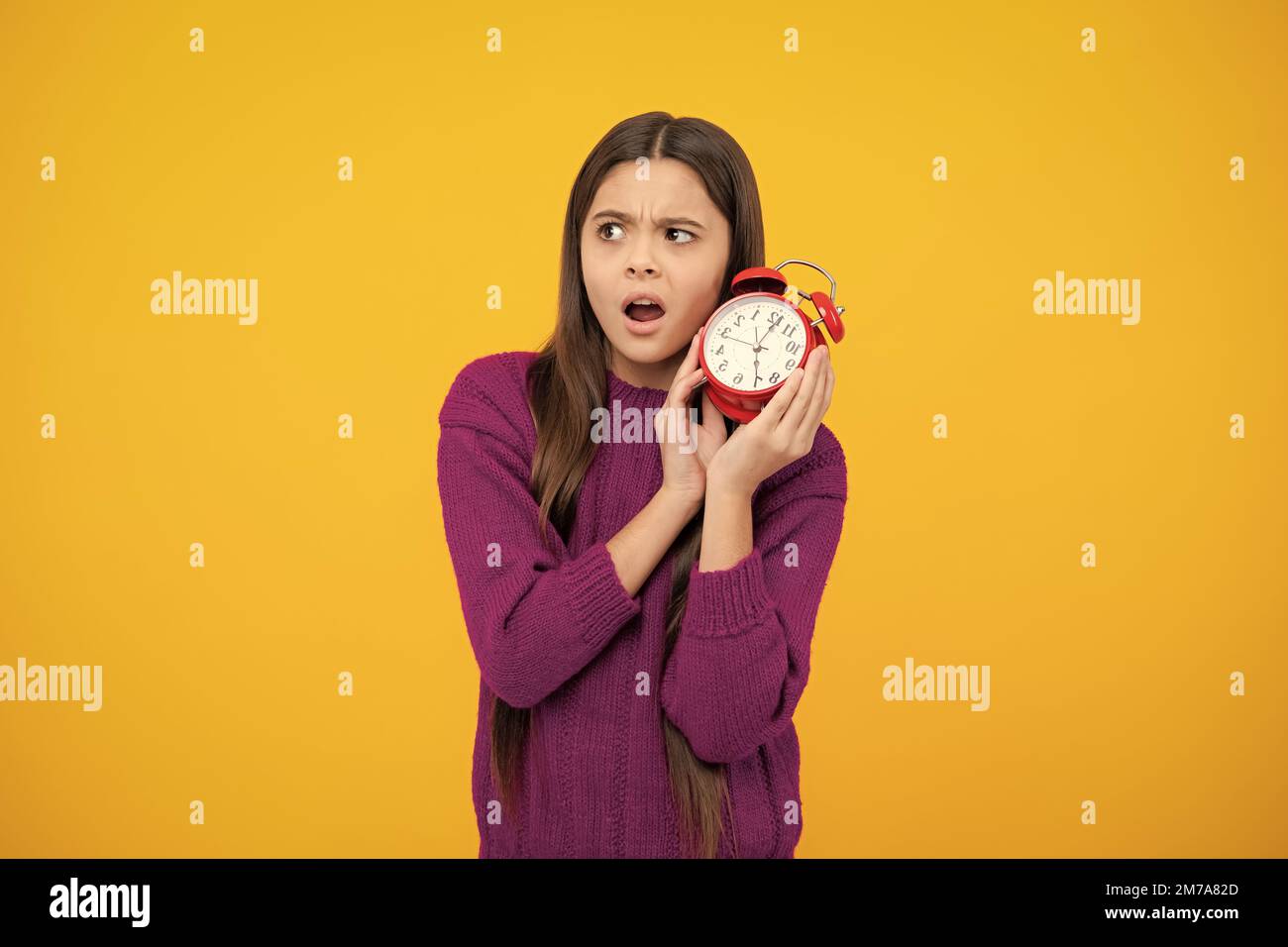 Teen girl 12, 13, 14 years old look at alarm clock. Time for shopping sales. Good morning, checking time. Angry teenager girl, upset and unhappy negat Stock Photo