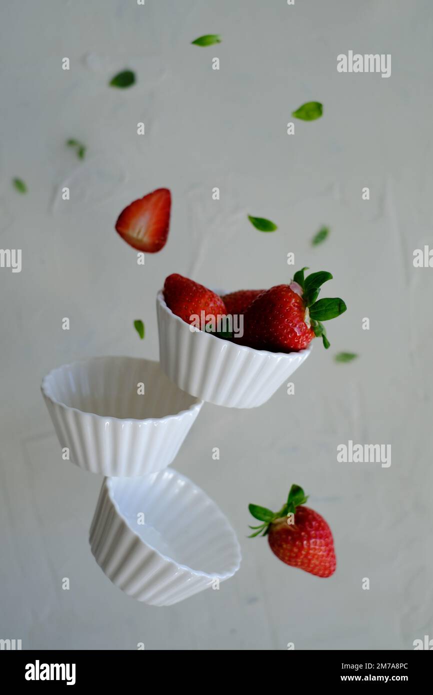 Strawberries in white bowls in levitation Stock Photo - Alamy