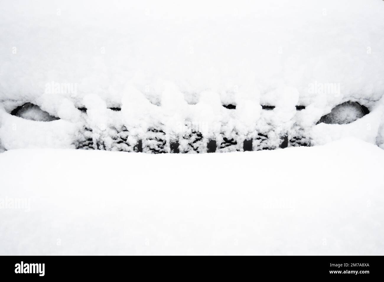 The snow covered grille and headlights of a black Jeep Wrangler buried after a blizzard in the Adirondack Mountains, NY USA Stock Photo