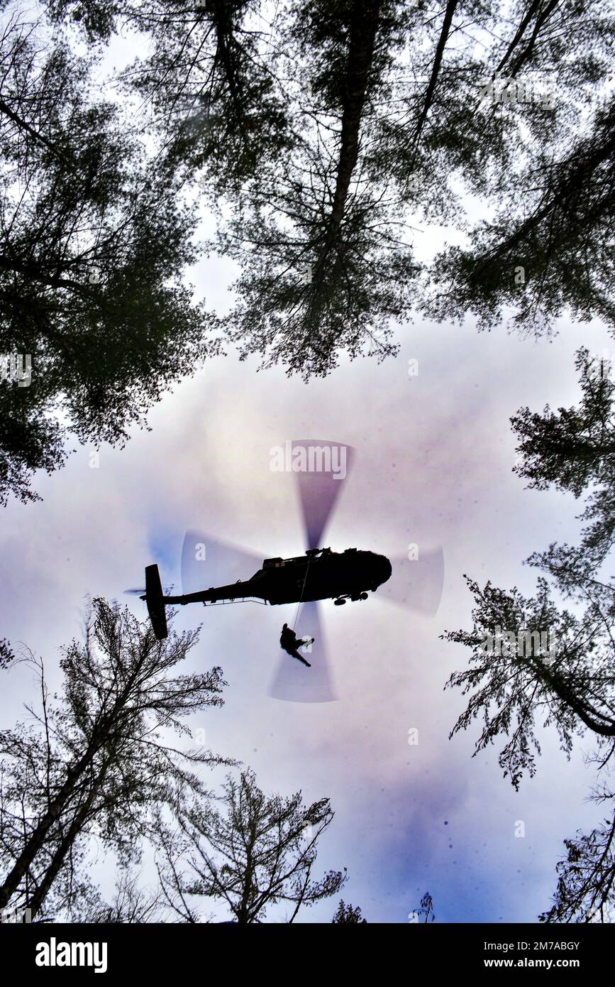 A Blackhawk from the 1-230th Assault Helicopter Battalion of the Tennessee National Guard hovers while medic SFC Cassandra Antes ascends during the SAREX 23 in Pickett State Park near Jamestown, TN Jan. 7, 2023. The group worked on tracking, locating, and evacuating missing persons as part of a training exercise with other military and civilian agencies to strengthen partnerships in a joint environment. (U.S. Air National Guard photo by Tech. Sgt. Teri Eicher) Stock Photo