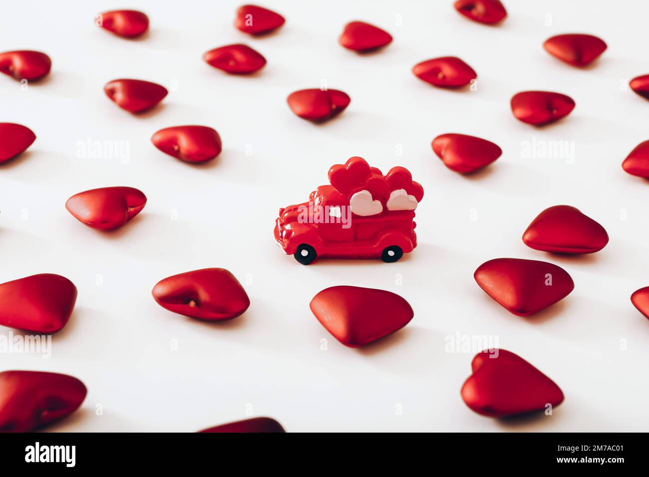 Miniature red car and many hearts on white background. Valentine Day concept Stock Photo