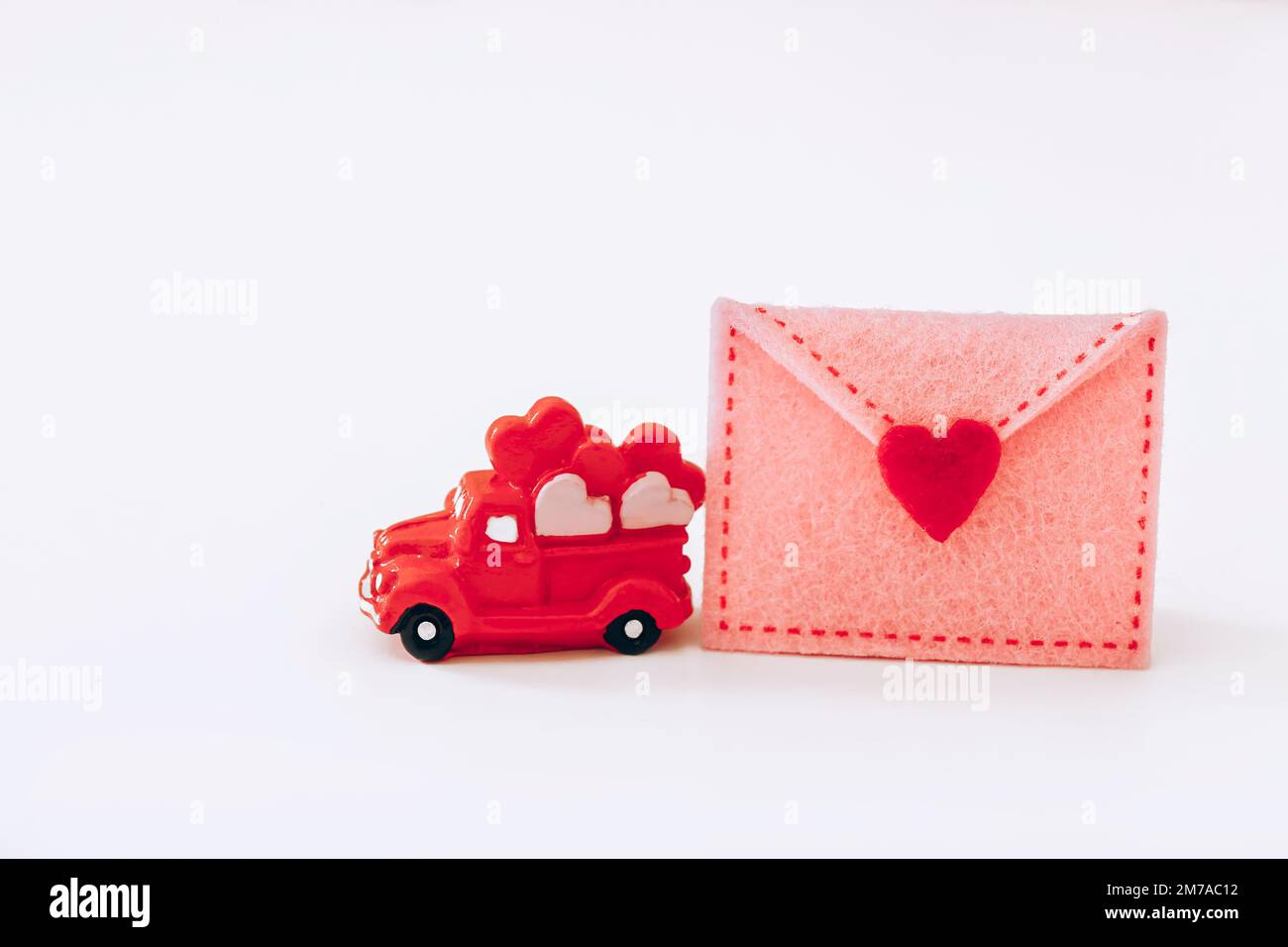 Miniature red car with hearts and felt envelope on white background. Valentine Day Stock Photo