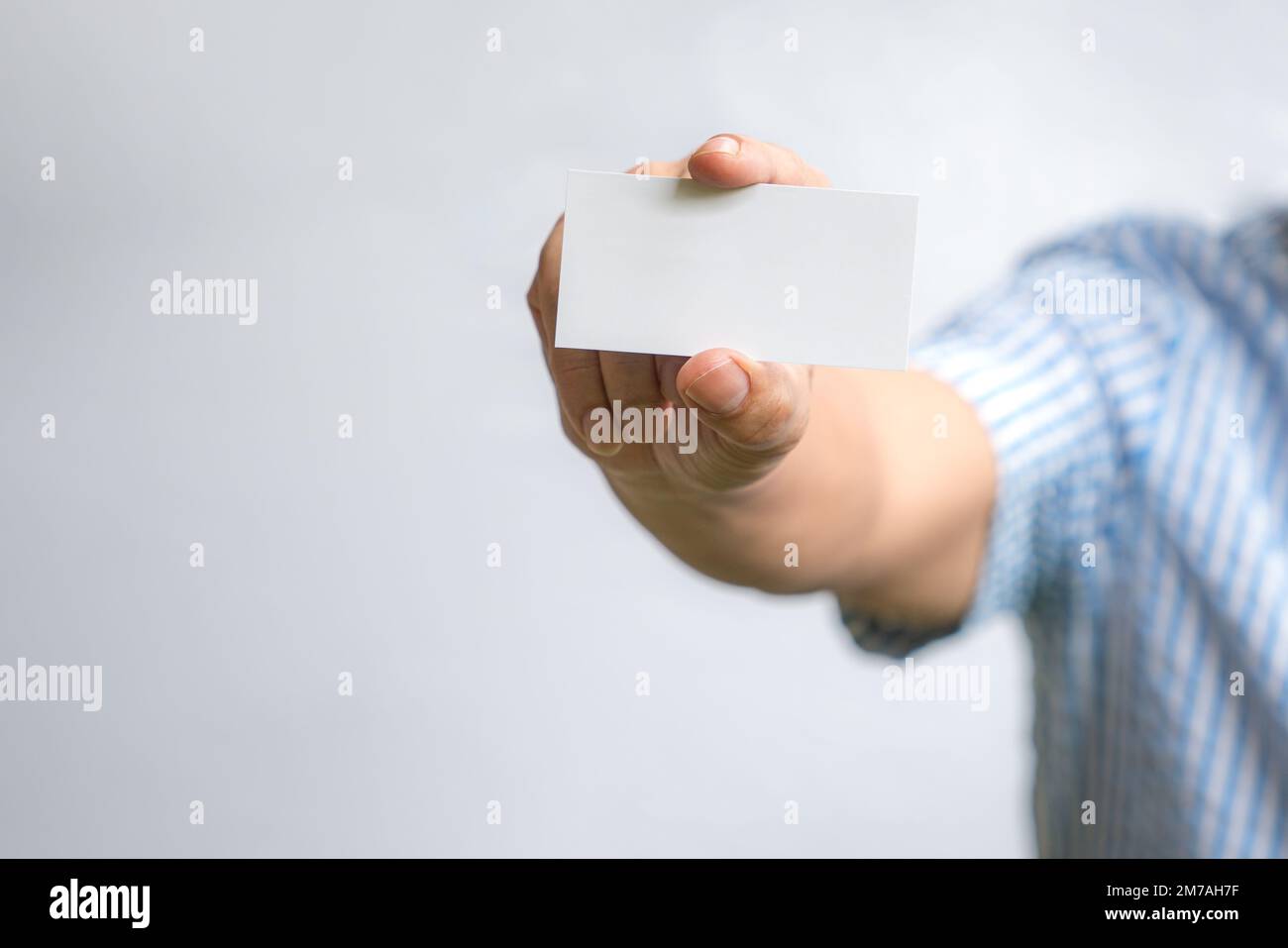 Man holding a white business card. On white background. Stock Photo