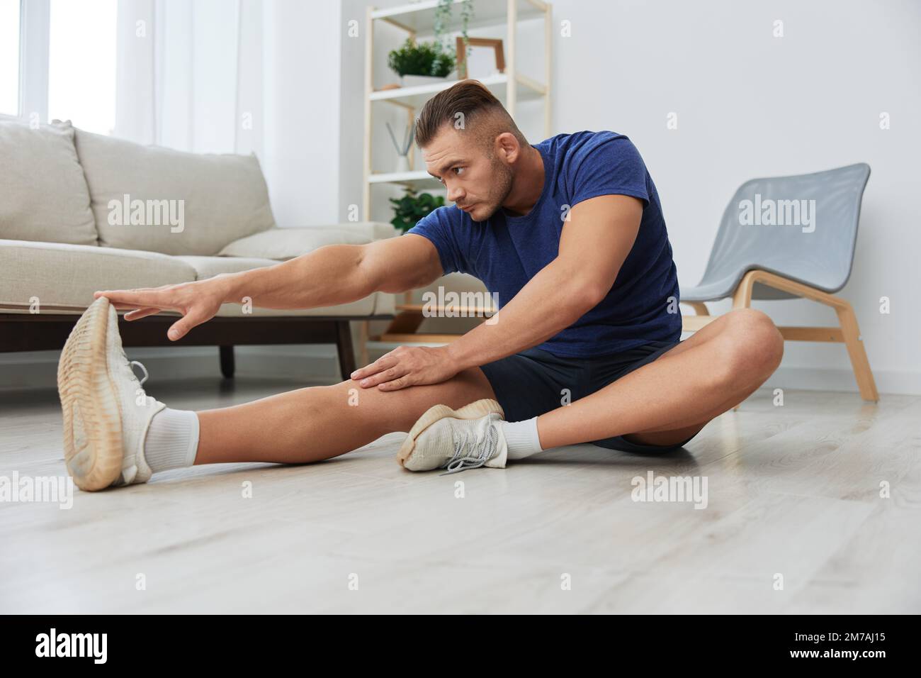 Man sportsman training at home, stretching exercises for arm, leg