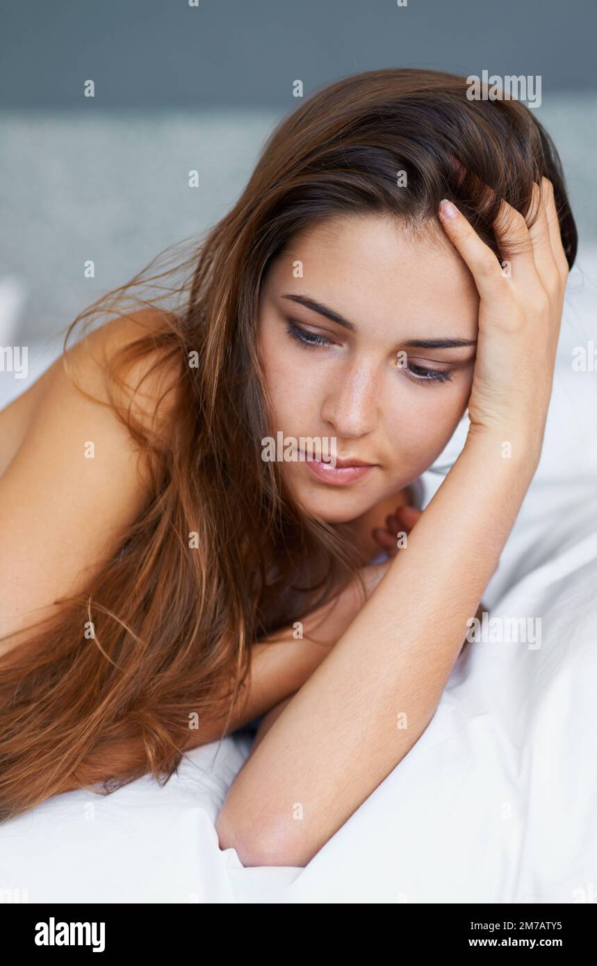 Lost in thought. A beautiful young woman lying on her bed looking thoughtful. Stock Photo