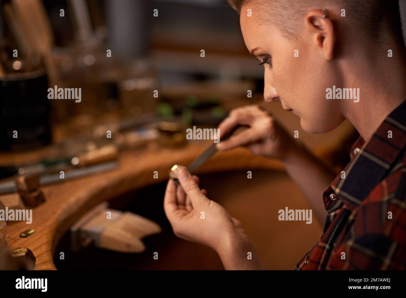 Focusing on getting the details right. A young woman working with tools at a wooden work station. Stock Photo