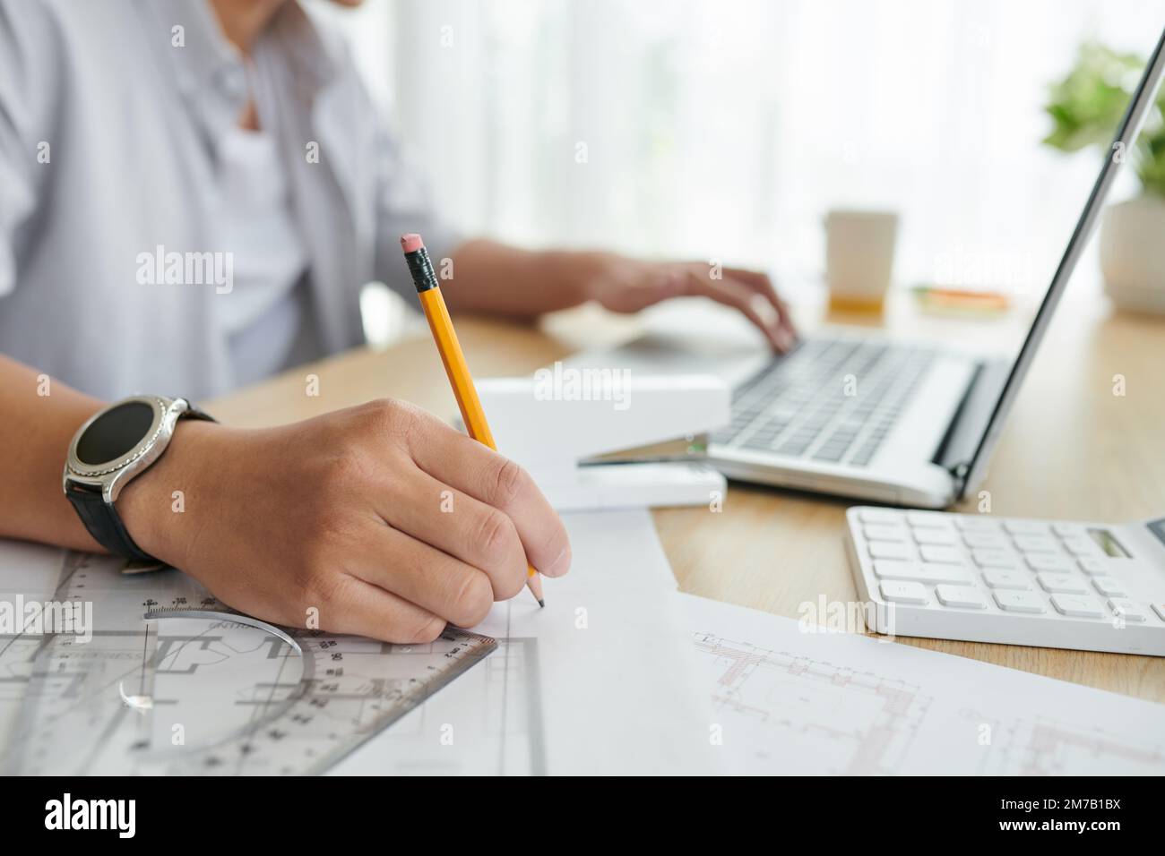Closeup image of architect making correction in construction plan on office table Stock Photo