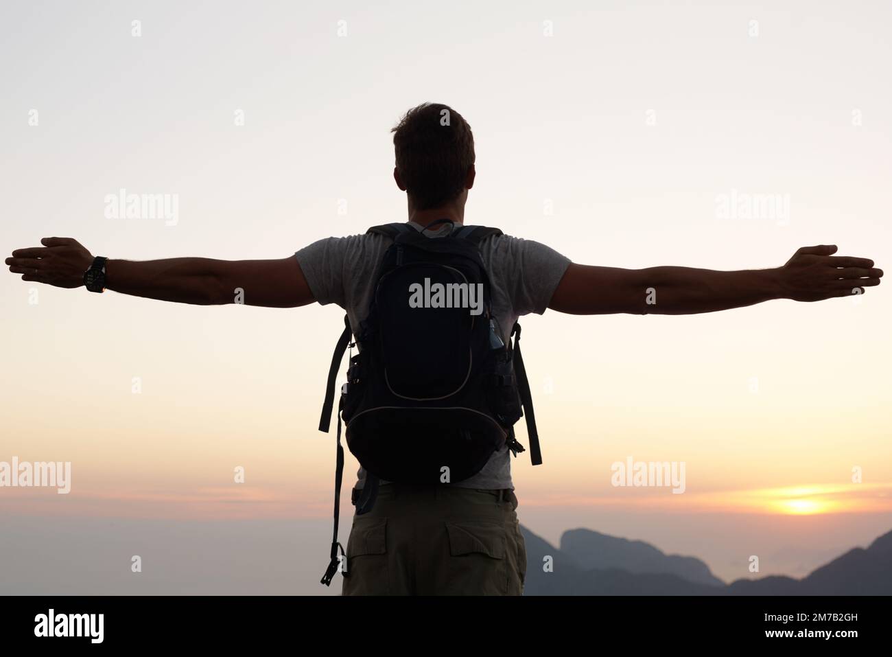 Taking a moment to breathe it all in. Silhouette shot of a young man standing against the sky. Stock Photo
