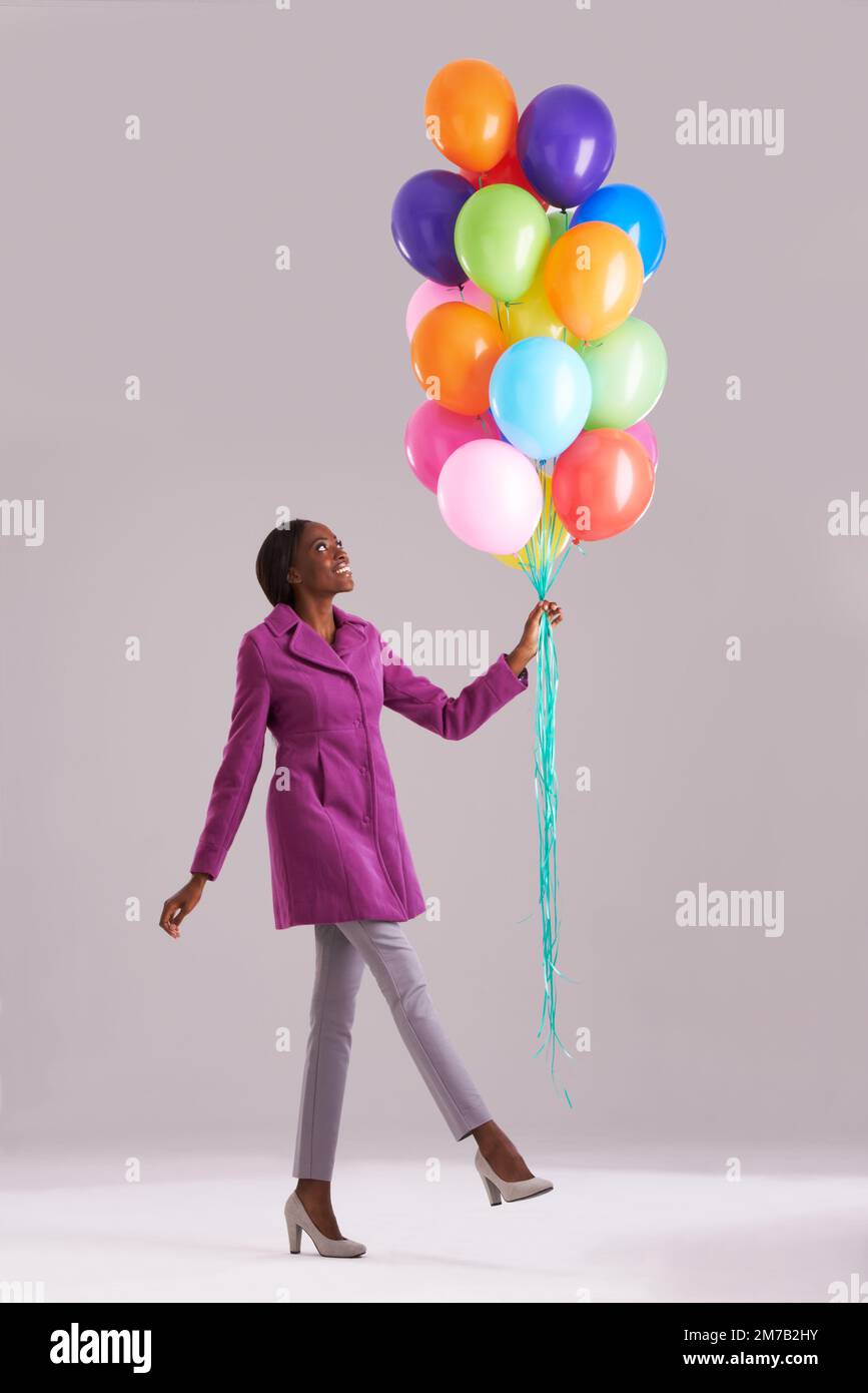 Live your life in technicolor. Studio shot of a happy young woman holding a bunch of balloons. Stock Photo