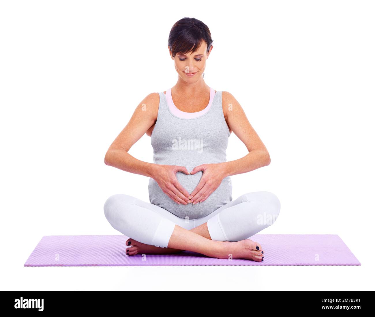 Calm and tranquility for mom and baby. A young expectant mother meditating peacefully while isolated on white. Stock Photo