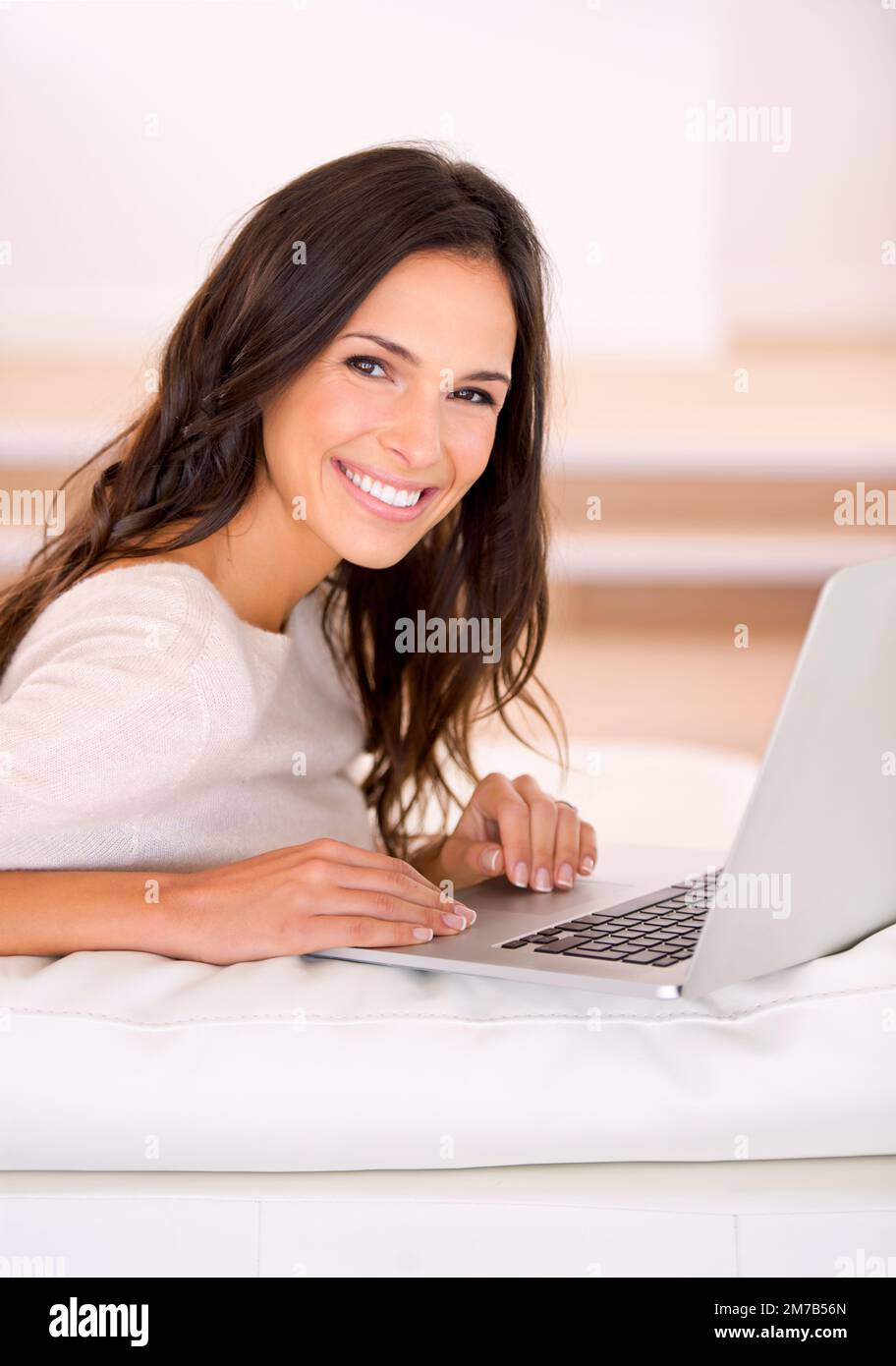 Keeping up with the latest chatter. a gorgeous young woman on a couch. Stock Photo