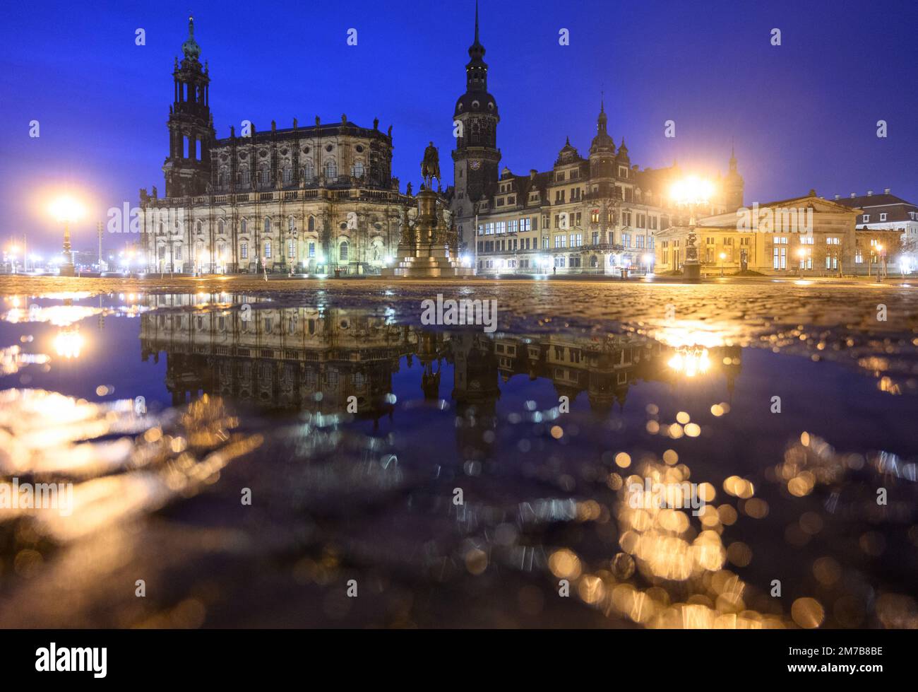 Dresden, Germany. 09th Jan, 2023. The Hofkirche (l-r), the equestrian statue of King Johann, the Hausmannsturm, the Residenzschloss and the Schinkelwache are reflected in a puddle on Theaterplatz in the Old Town in the morning. Credit: Robert Michael/dpa/Alamy Live News Stock Photo