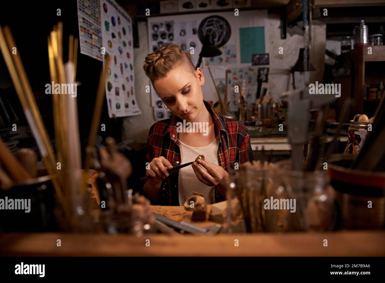 When life gives you hands, MAKE. A young woman working with tools at a wooden work station. Stock Photo