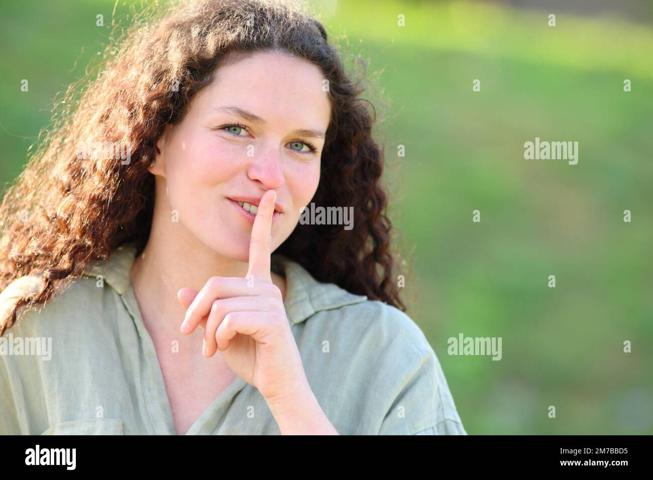 Happy Woman Asking For Silence Outside With Finger On Lips Stock Photo