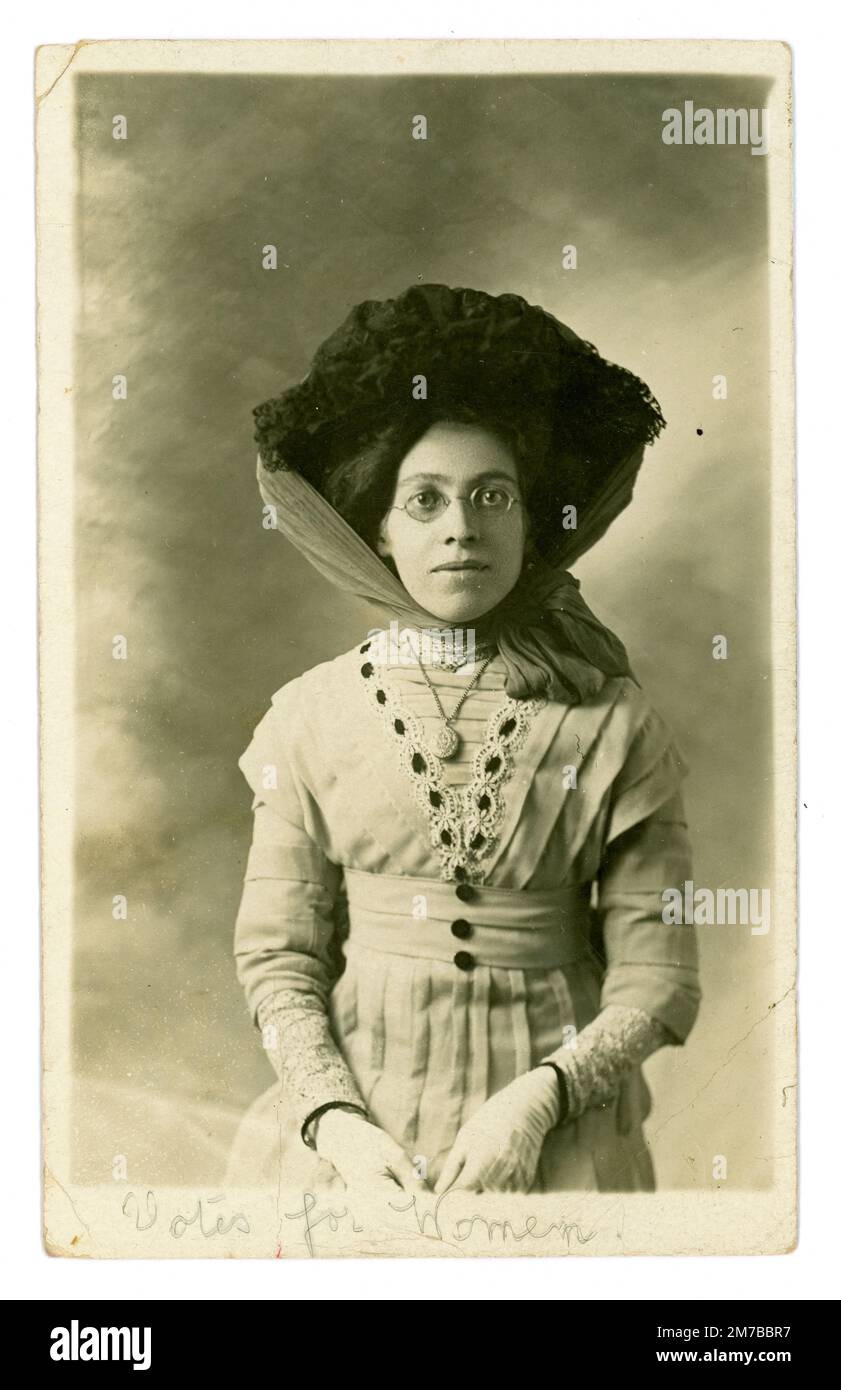 Original and clear studio portrait postcard of a strong willed serious / earnest looking young Edwardian era woman called Katie, who has written 'Votes for Women' below her image on a postcard. Perhaps she was a suffragette or a suffragist or just a sympathiser of the cause. She wears a large hat tied with a scarf. She lived in London. From the studio of Laffitte 184 Western Road, Brighton, Sussex, England, posted from South Tottenham, London, U.K. Dated / posted 13th Feb 1911. Stock Photo