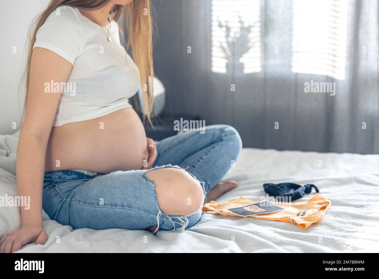Pregnant woman looking ultrasound photo album on bed Stock Photo by  ©geargodz 250442426