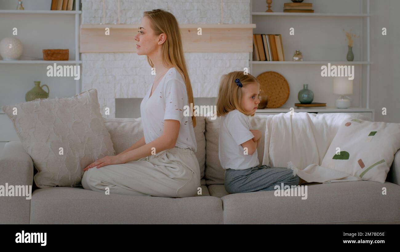 Little abuse child girl sad upset daughter adopted kid ignore unhappy offended mother family disagreement sitting at home couch looking to different Stock Photo