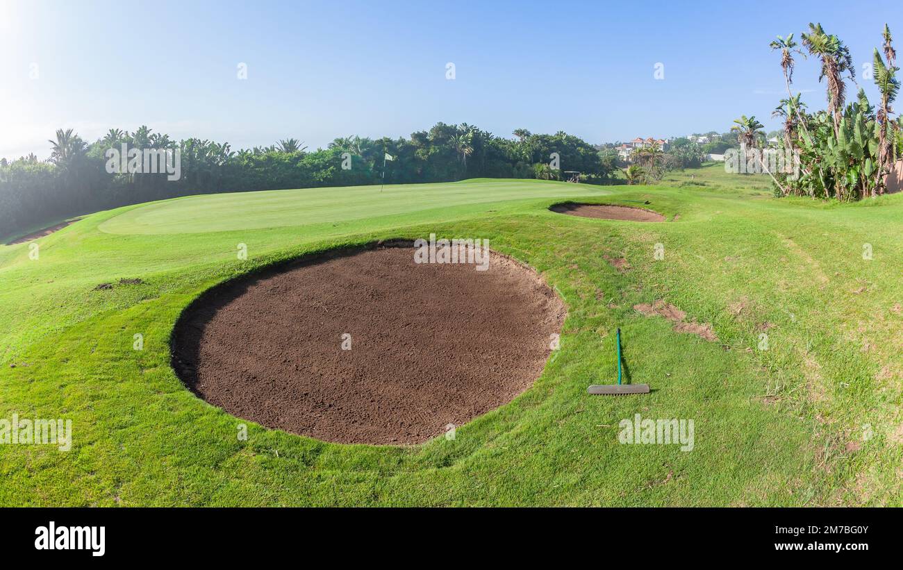 Golf Course scenic layout of coastal beach hole putting green surrounded by green vegetation summer blue sky landscape. Stock Photo