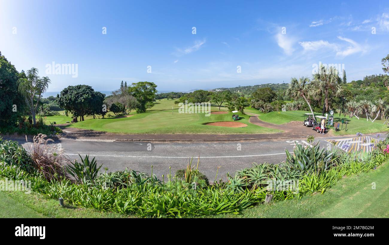 Golf Course scenic layout of coastal design tee box  putting green surrounded by green  trees vegetation summer blue sky landscape. Stock Photo