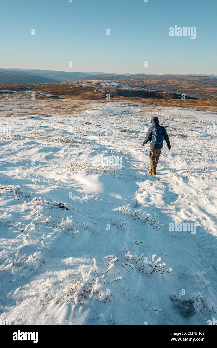 man hiking in beautiful winter landscape snow view from mountain Litjskarven in Norway in sunnlight Stock Photo