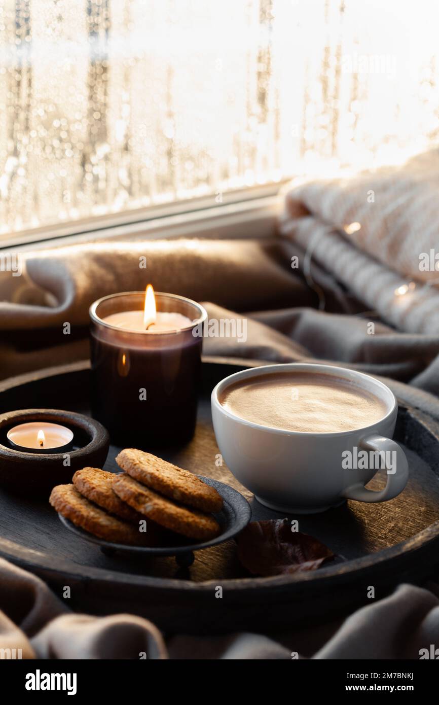warm cozy window arrangement, winter or autumn concept, coffe, candles throw lights Stock Photo