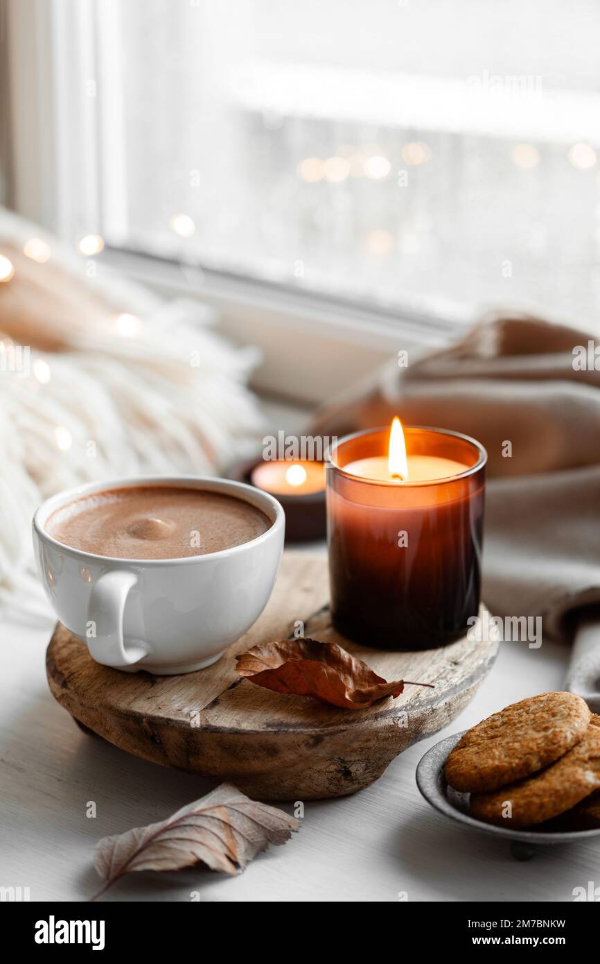 warm cozy window arrangement, winter or autumn concept, coffe, candles throw lights Stock Photo
