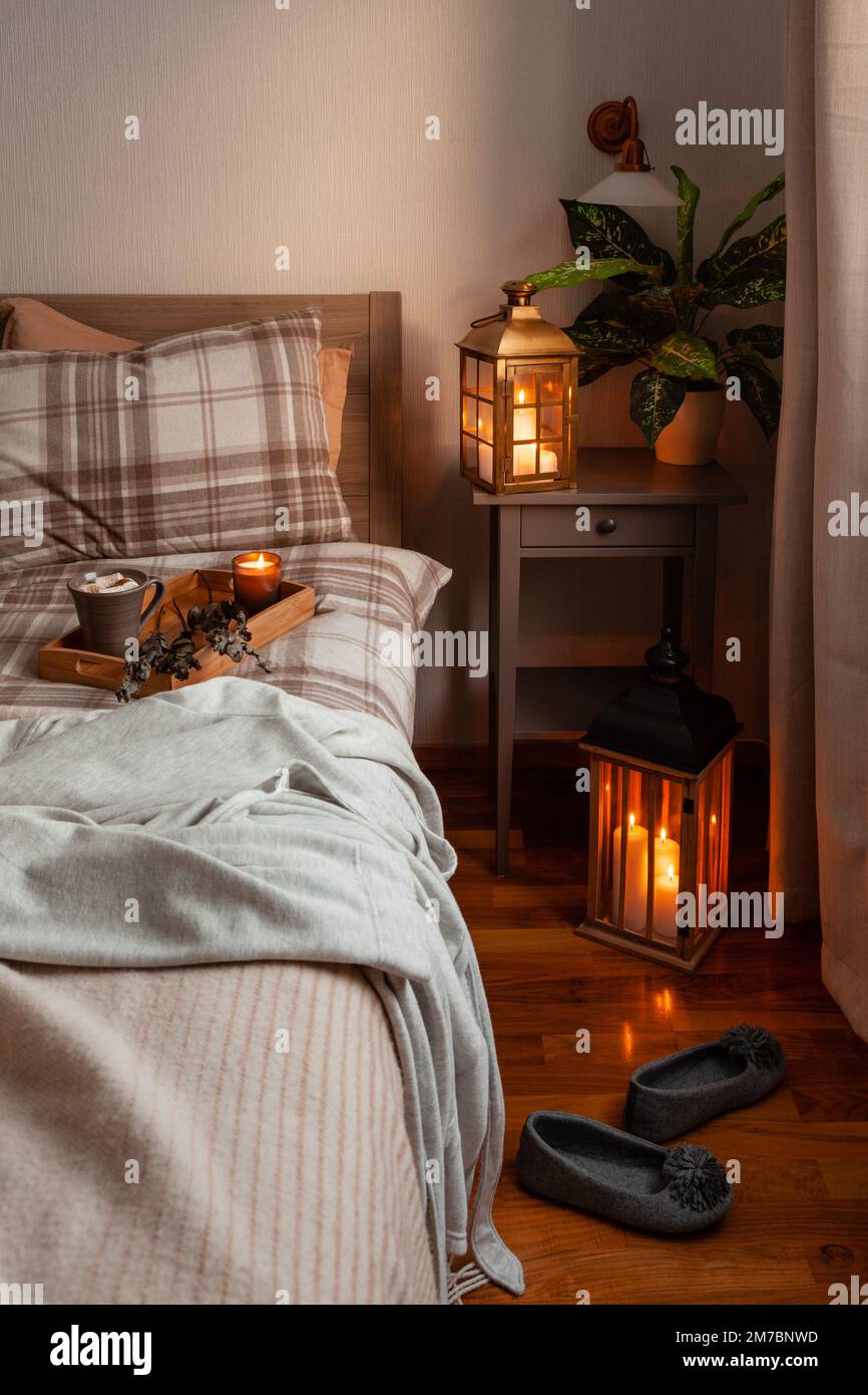cozy scandinavian bedroom interior in natural tones, blanket lantern houseplants Stock Photo
