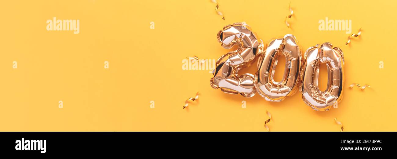 Banner with number 200 golden air balloons with ribbons confetti on a yellow background. Stock Photo