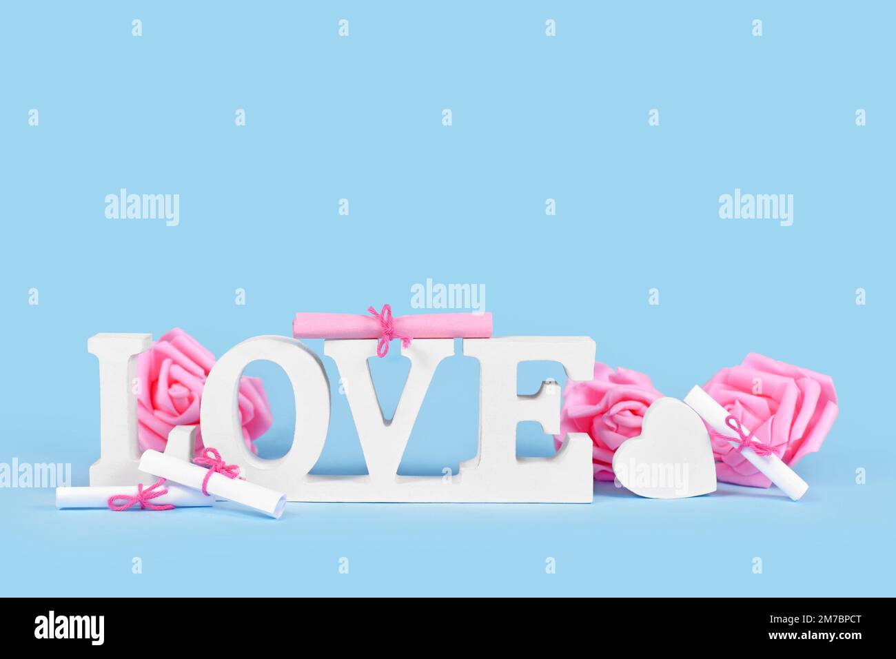 White wooden word LOVE with roses on blue background with copy space Stock Photo