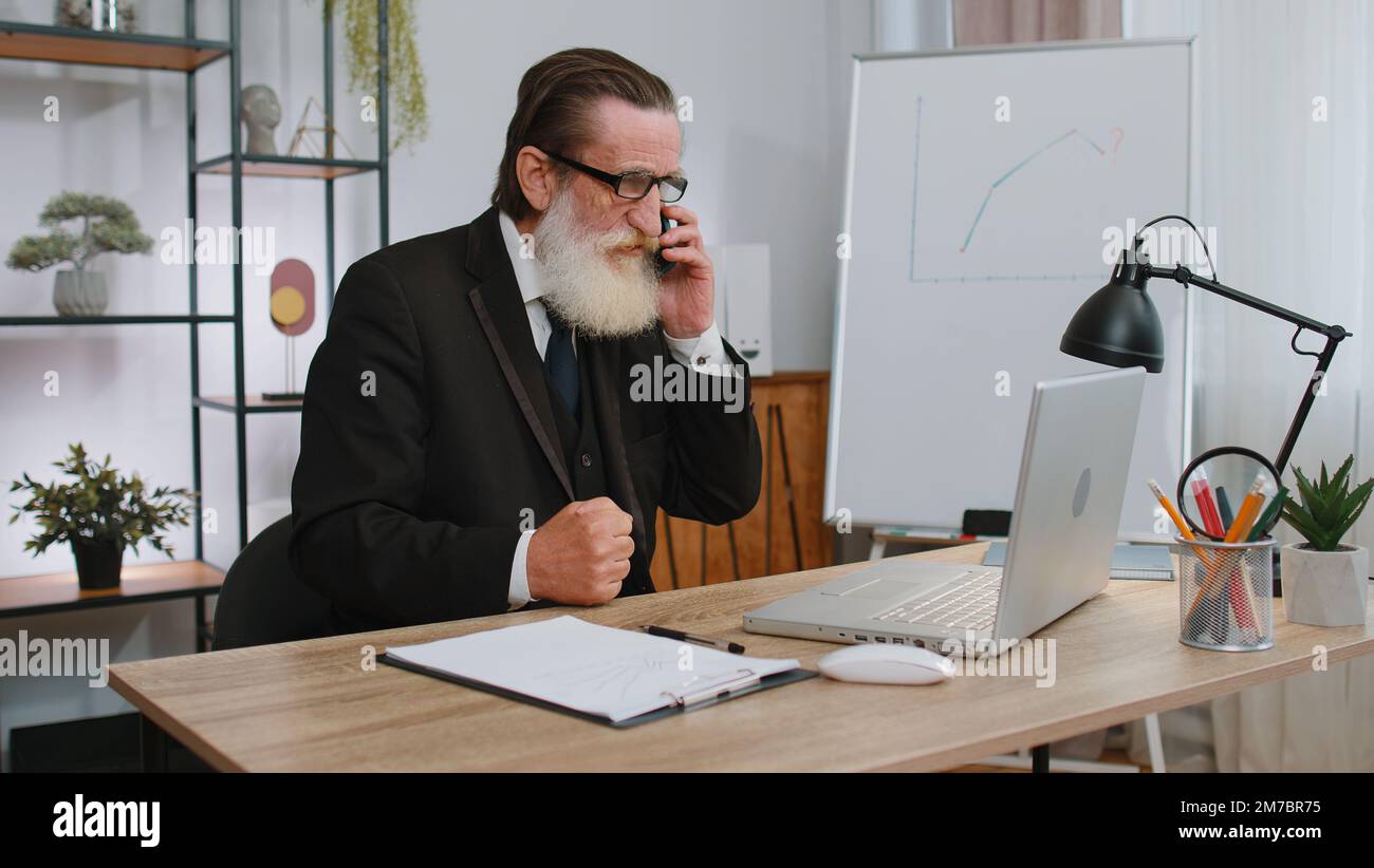 Conflict, quarrel, negotiation. Angry senior businessman ceo making webcam  laptop mobile phone online call at home office desk. Upset mad freelancer  grandfather old man talking conversation indoors Stock Photo - Alamy
