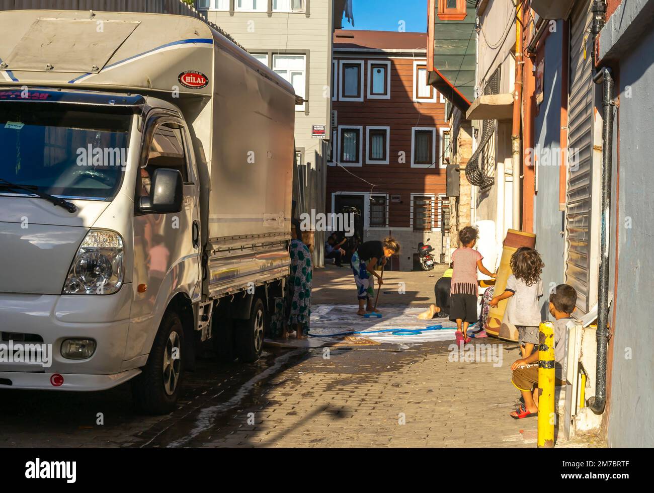 A young woman washing a carpet on the ground in ront of the house
