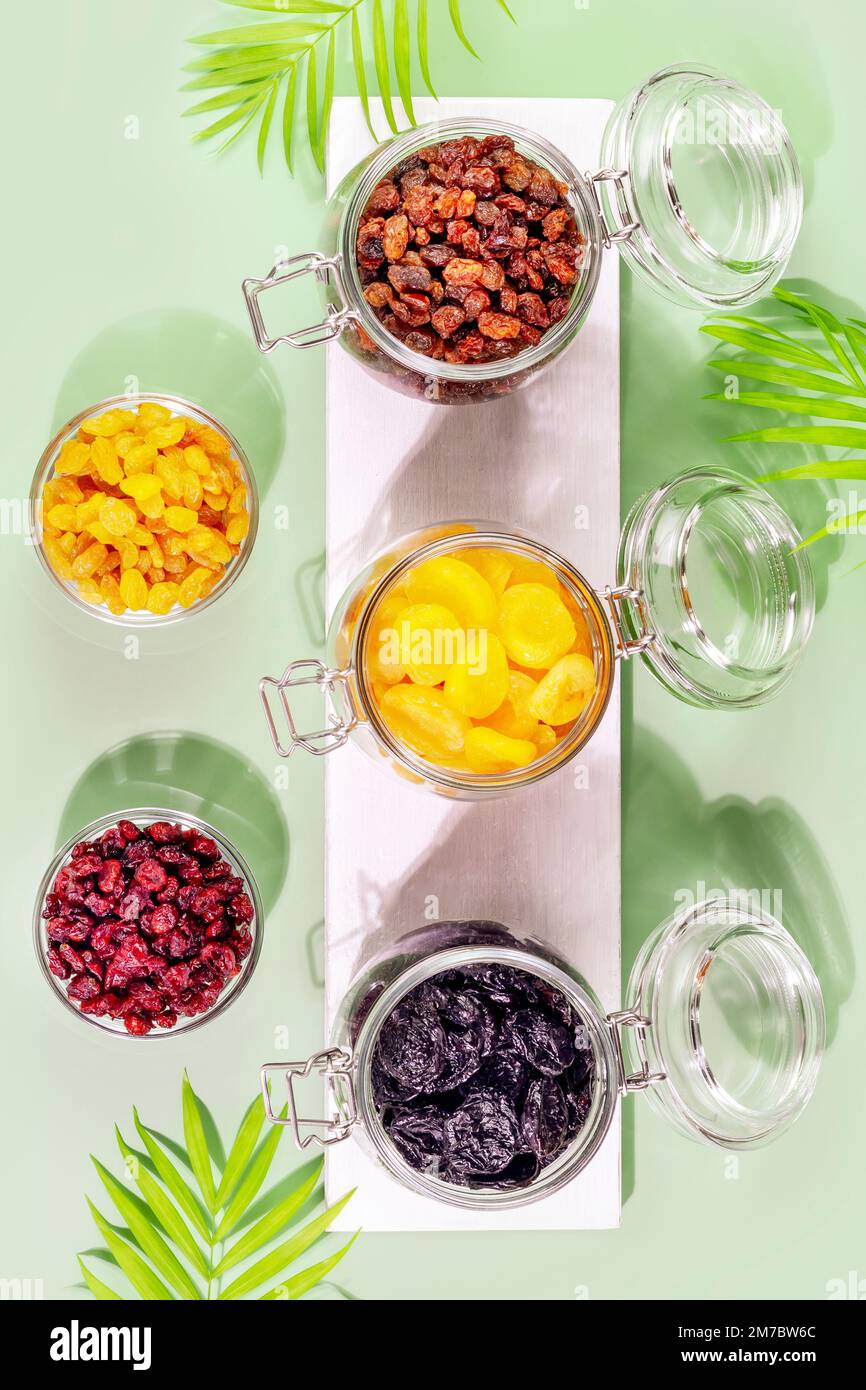 Dry fruits assortment on blue background with palm leaves. Healthy
