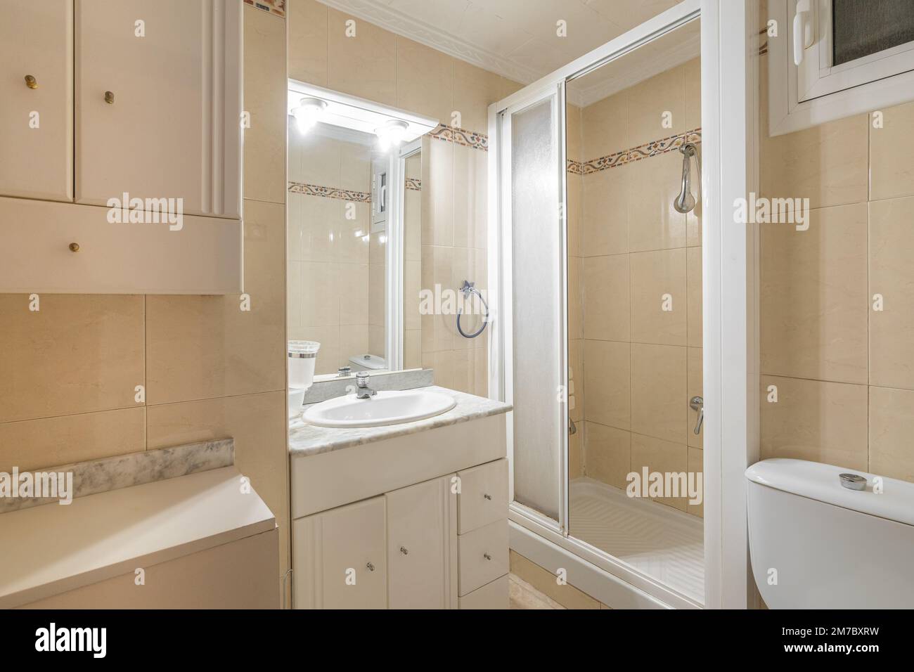 bathroom-is-bright-by-lamps-above-small-mirror-with-light-beige-tile
