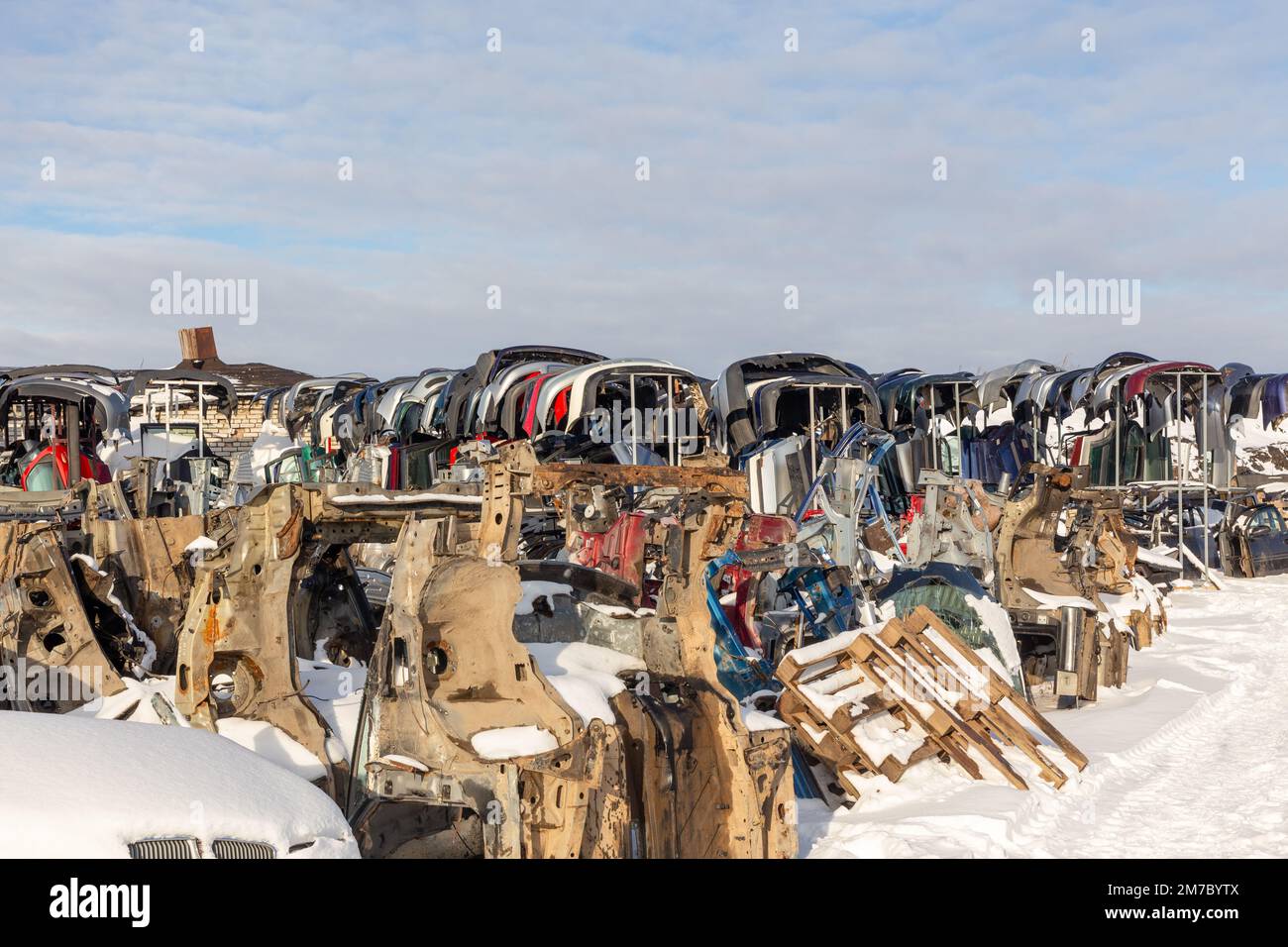 Disassembled cars on a car dump are on sale for spare parts. A stack of spars and bumpers. Trade in used spare parts is a common business in developin Stock Photo