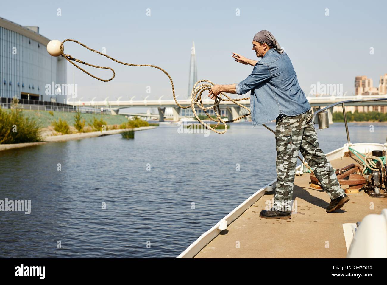 Full length side view of man standing on boat and throwing line with