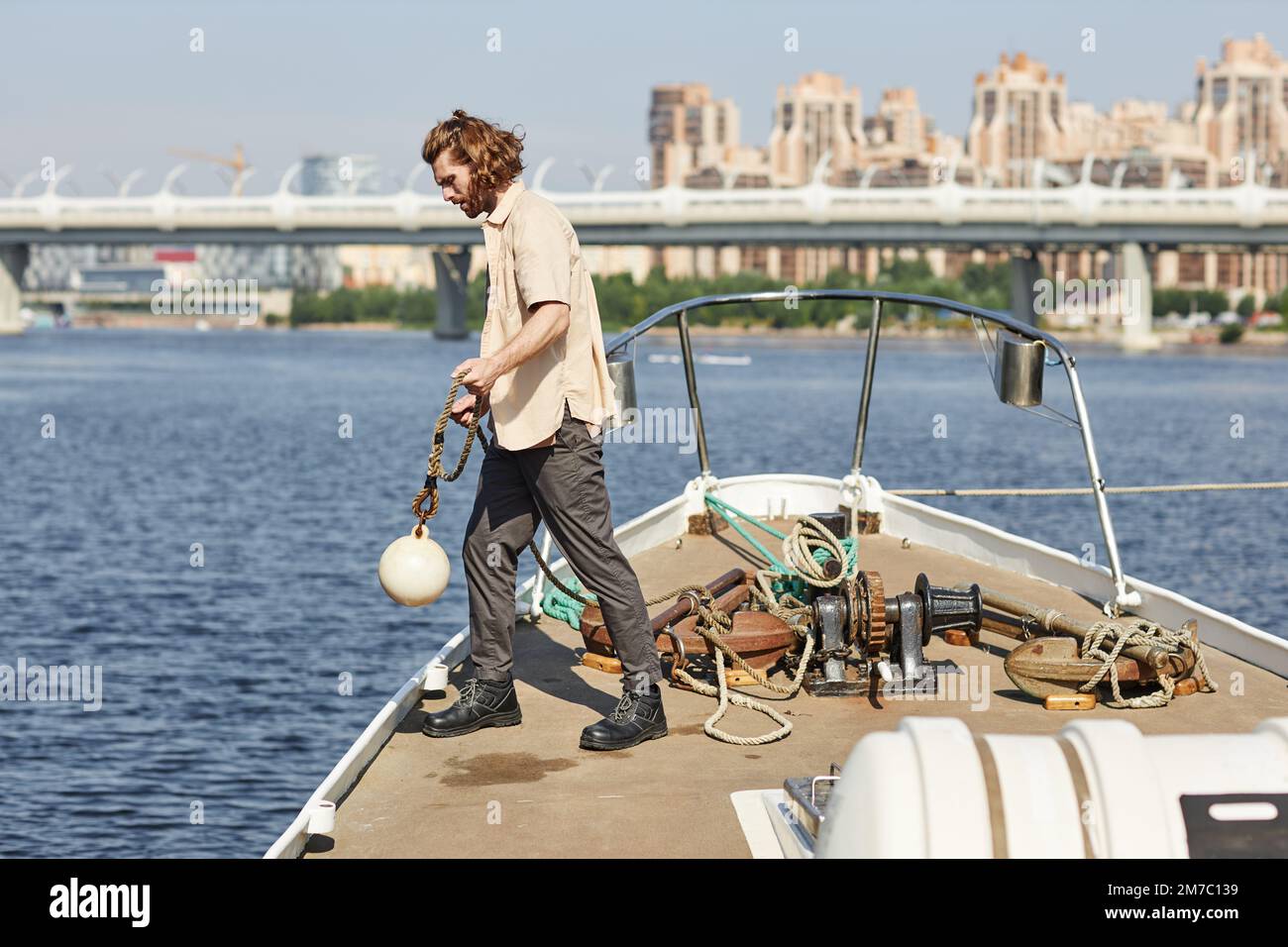 Full length side view of handsome young man standing on boat and