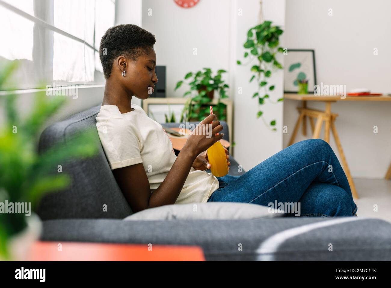 Thoughtful young african woman sitting on sofa at home Stock Photo