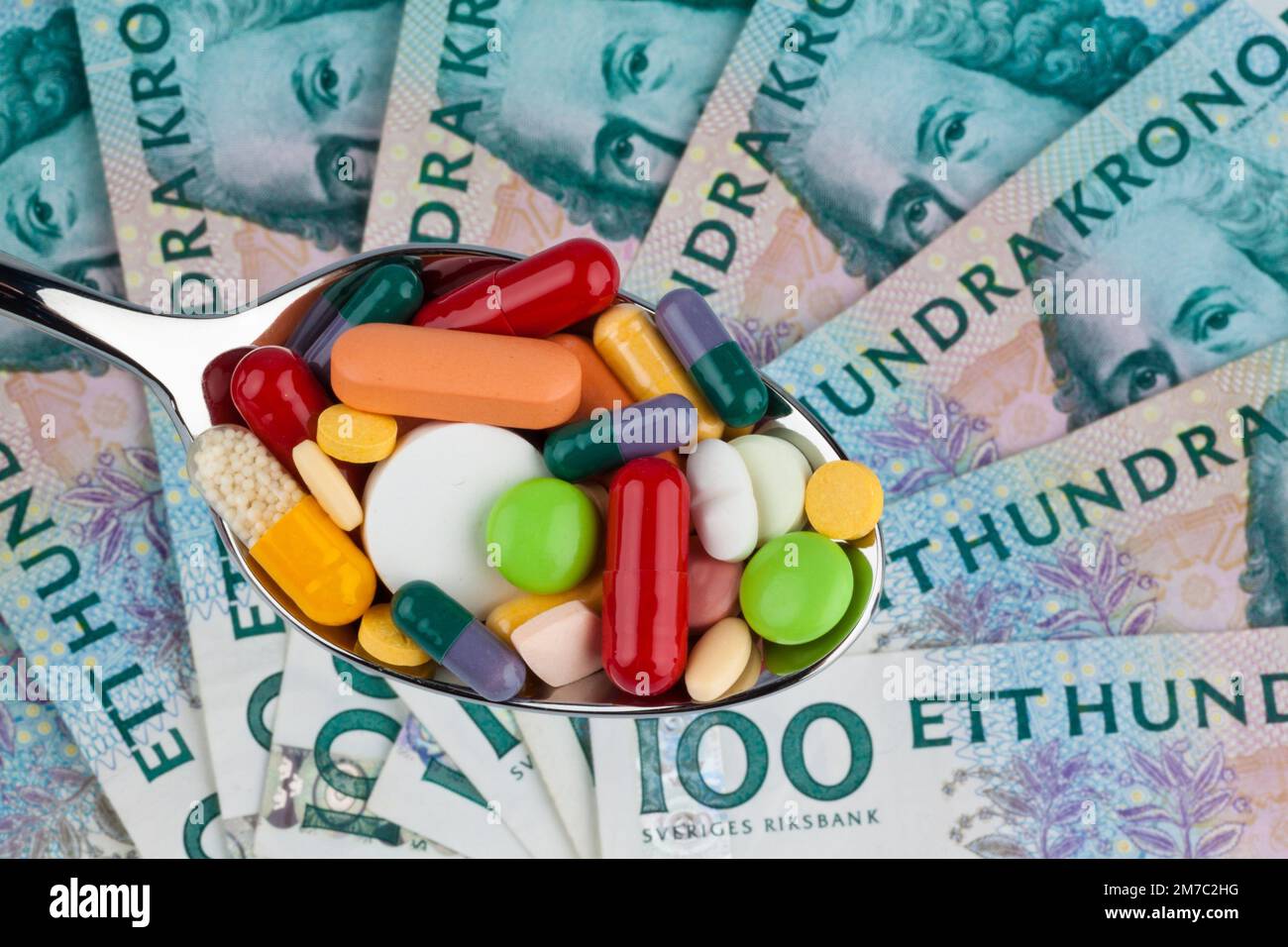colourful pills on a spoon against Swedish krona, cutout Stock Photo